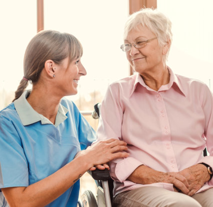 caregiver talking with an elderly woman in wheelchair
