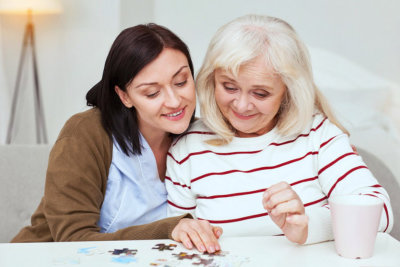 middle aged woman playing puzzles with an elderly woman